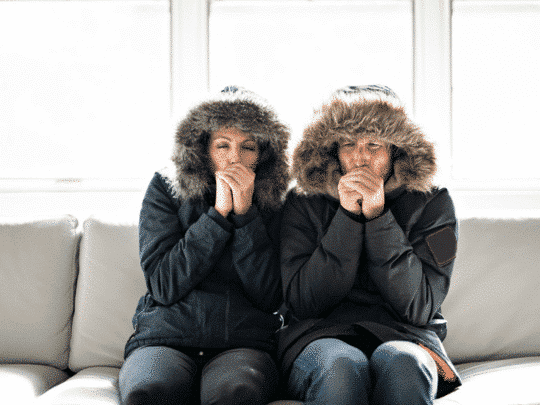 couple on couch wearing winter jackets because heater is broken